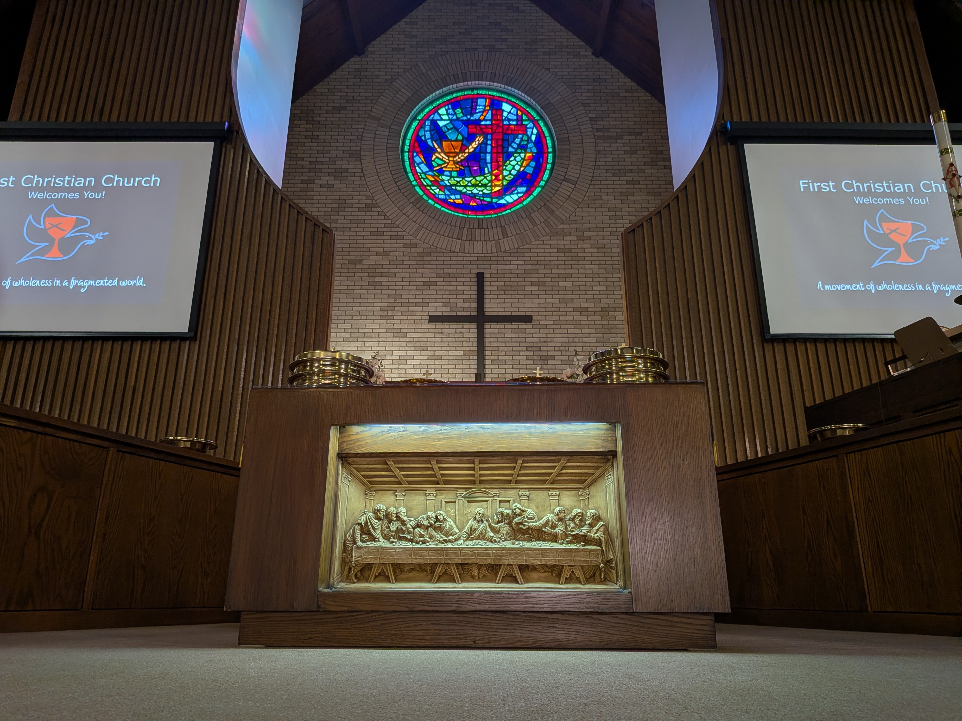 First Christian Church sanctuary — altar with Last Supper relief, cross, and stained glass chalice window